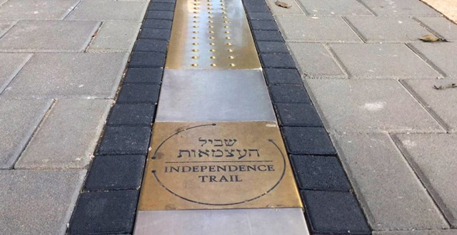סימון בפליז מוזהב לאורך שביל העצמאות. צילום שוש להב